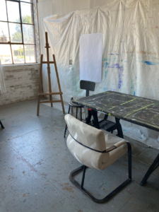 studio with easel, table, and chair
